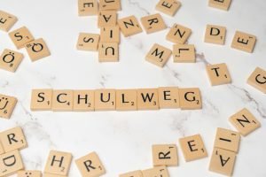 Scrabble tiles arranged to spell 'Schulweg' on a white marble surface, creative layout.
