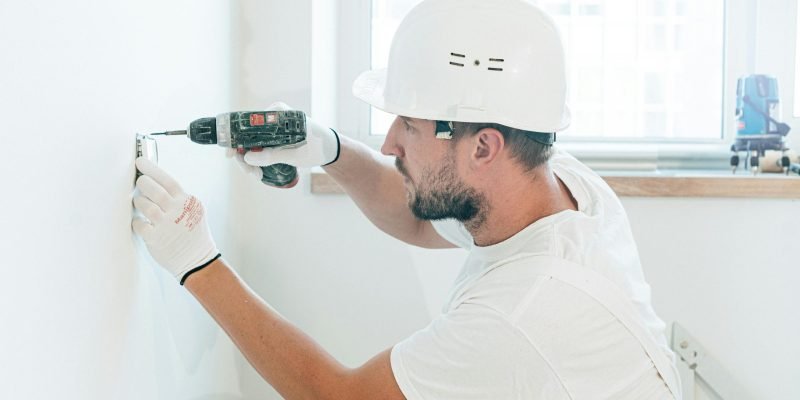 Carpenter skillfully uses a drill wearing safety gear during a renovation project indoors.