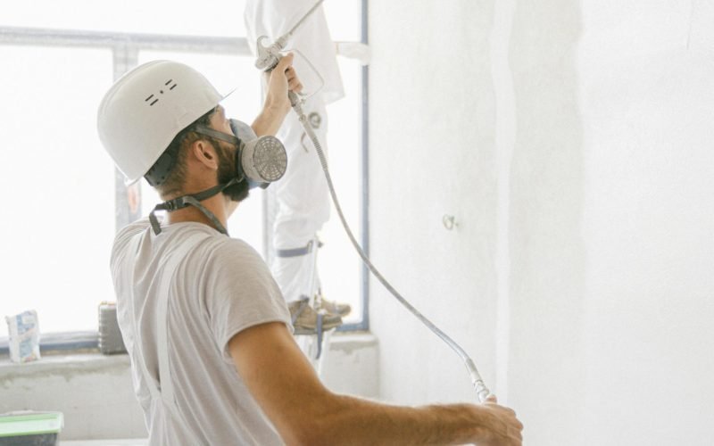 Two professional painters working indoors on wall renovation and painting project.